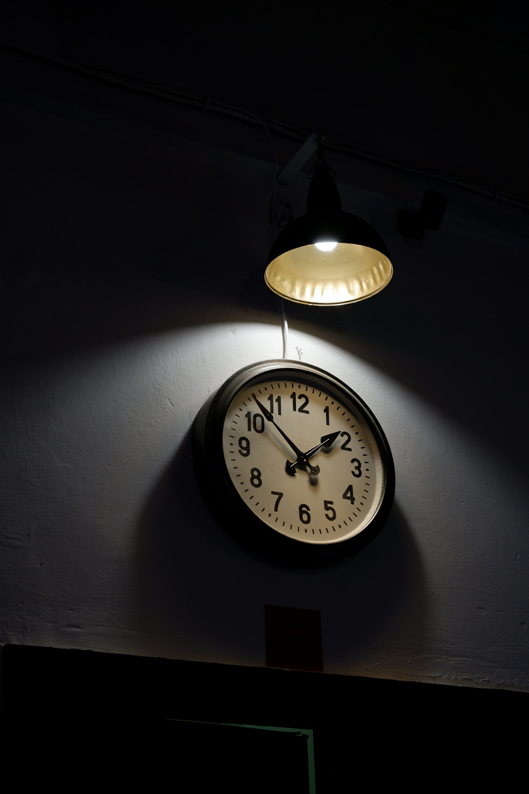 large wall clock close-up. The large wall clock is illuminated by a large beautiful wall lamp. home interior